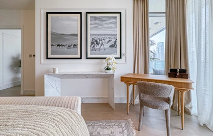 Bedroom suite with writing desk, framed art and layered curtains