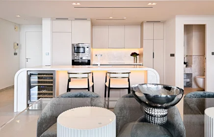 Open-plan apartment kitchen with curved island and wine cooler, finished by Heritage Turnkey