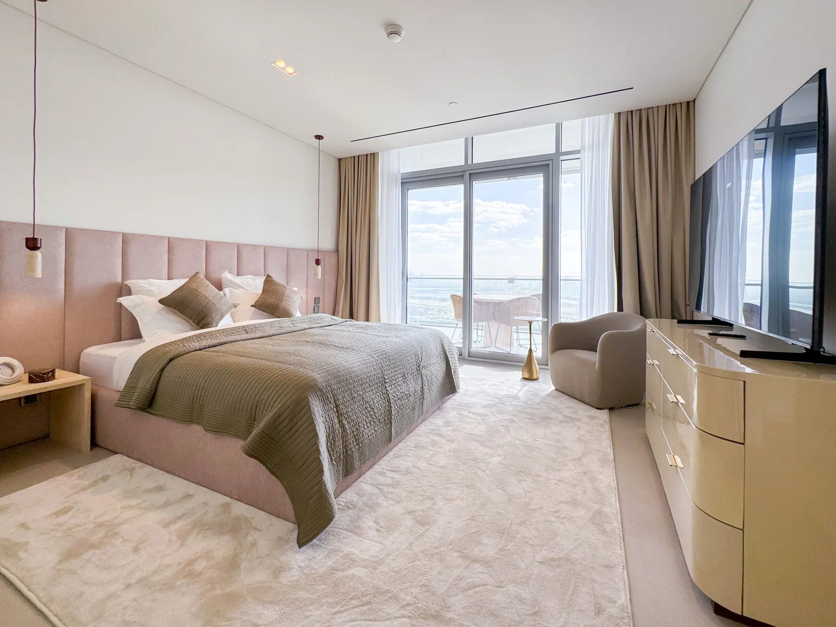 Master bedroom with upholstered headboard, sea-view windows and built-in TV unit