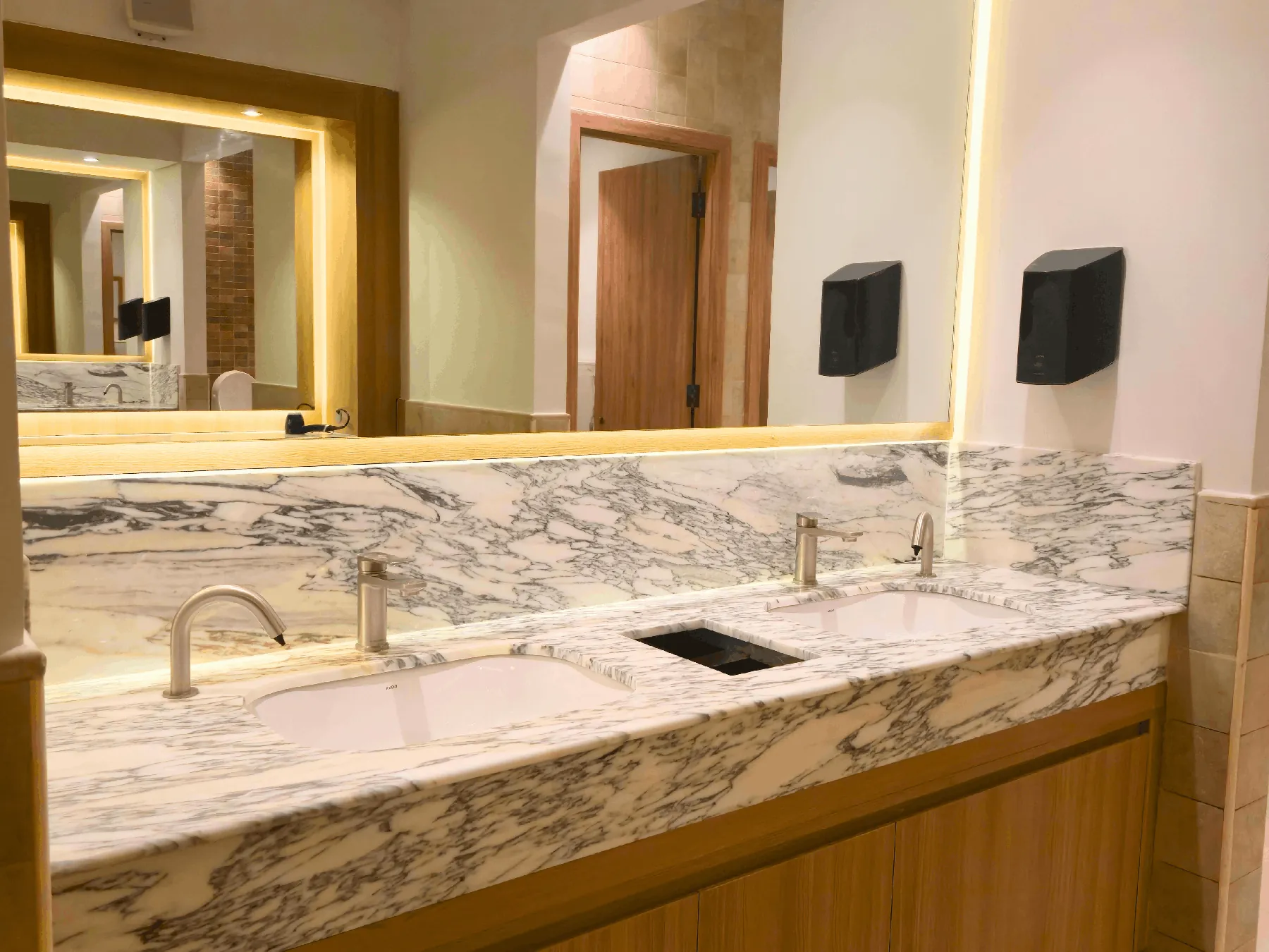 Marble vanity with twin basins and illuminated mirror in a commercial washroom