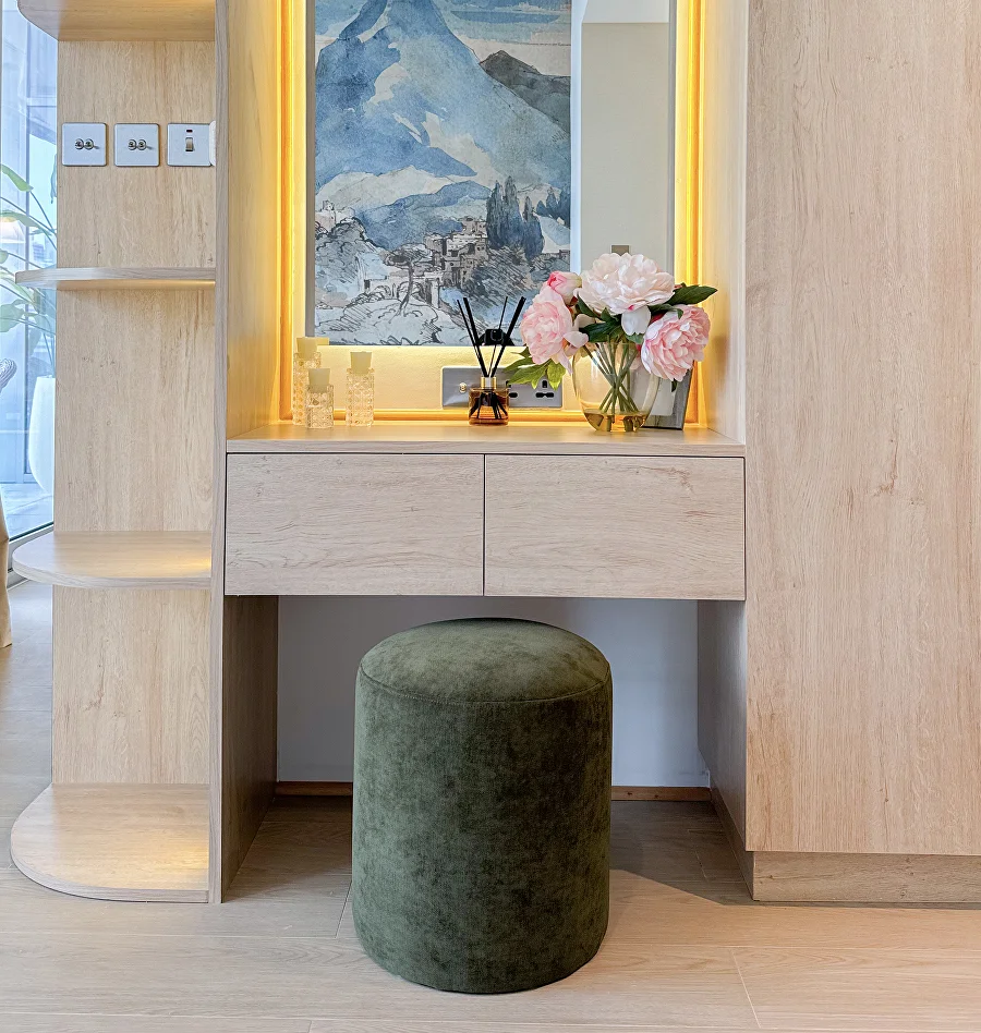 Dressing table with illuminated mirror and upholstered stool in a renovated apartment