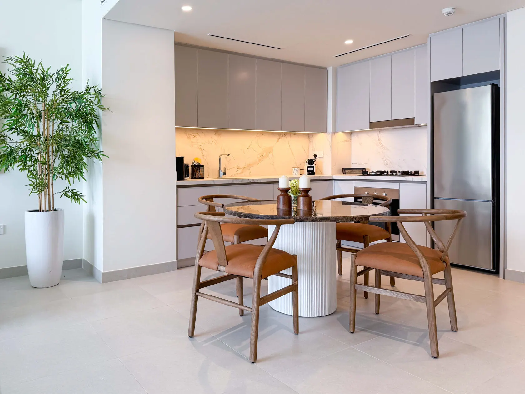Modern kitchen and dining area with marble splashback and round table in a renovated Dubai apartment