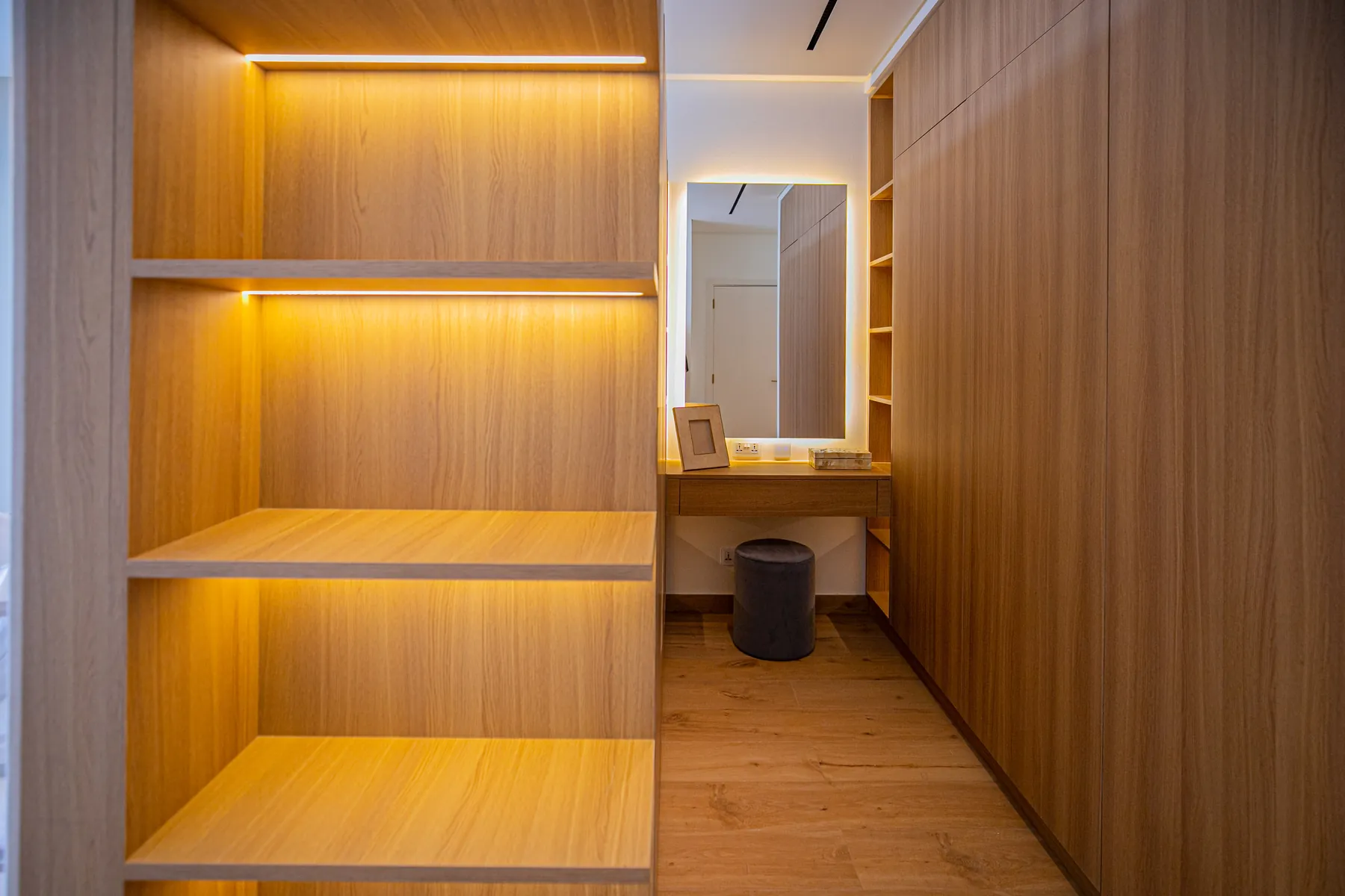 Custom timber joinery with LED-lit shelving and a walk-in wardrobe